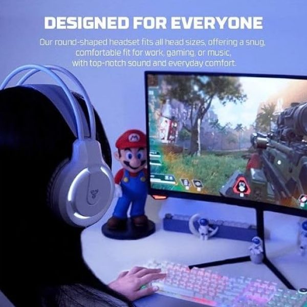 A person wearing a white over-ear gaming headset with blue LED lighting sits at a desk using a computer. The scene includes a monitor showing a video game, a keyboard, and small Mario-themed figurines on the desk.