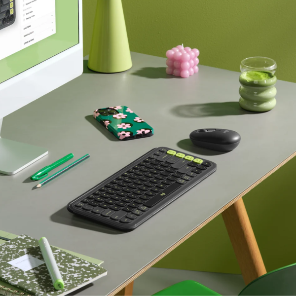 Logitech POP Icon Wireless Keyboard ENOnly and Mouse Combo
A wireless computer keyboard with a black body and lime green keycaps is shown on a gray desk alongside a mouse, phone, and other desk accessories in a styled office setting.