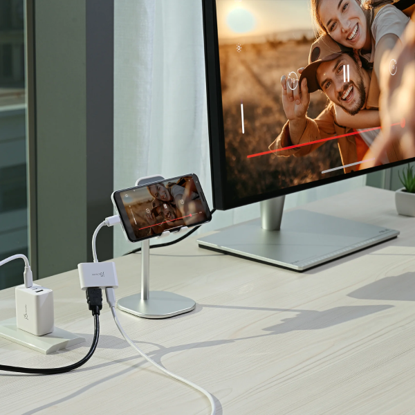 Tablet stand with phone holder on a desk next to a computer monitor displaying a couple.