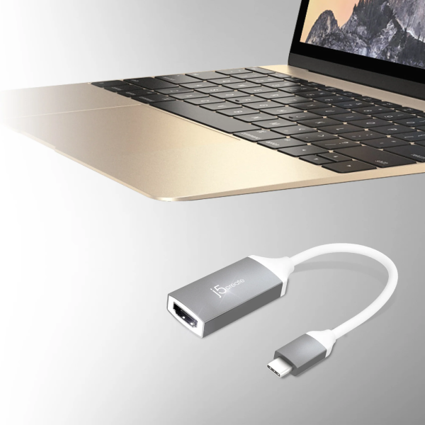 A silver and white USB-C to HDMI adapter cable shown below a partially visible gold laptop on a light gray background.