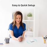 A woman in a blue top sits at a white desk holding a smartphone, with the text 'Easy & Quick Setup' above her. On the desk in front of her is a small white rectangular electronic device with a faint circular light effect around it.