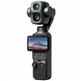 A black Osmo handheld gimbal camera with a dual-lens front and an attached screen displaying a mountain landscape, shown on a solid white background.