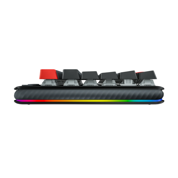 Logitech G517 Lightspeed TKLWireless A close-up side view of a mechanical keyboard featuring a black and gray textured body, black keycaps, red side switches, and a vibrant RGB rainbow light strip along the bottom edge.