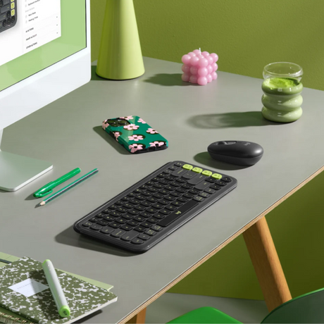 Logitech POP Icon Wireless Keyboard ENOnly and Mouse Combo
A wireless computer keyboard with a black body and lime green keycaps is shown on a gray desk alongside a mouse, phone, and other desk accessories in a styled office setting.