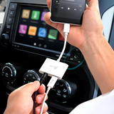 A close-up of a person's hands using a white 3-in-1 USB adapter to charge a smartphone and another device in a car. The adapter is labeled with the brand 'JYP'.
