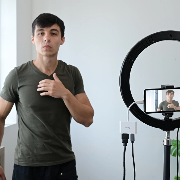 Man giving a thumbs up in front of a ring light setup with a smartphone