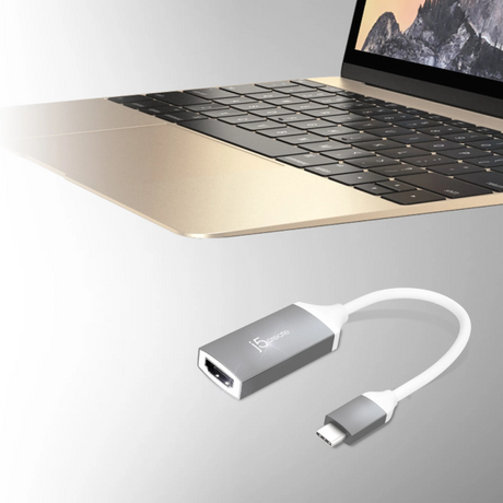 A silver and white USB-C to HDMI adapter cable shown below a partially visible gold laptop on a light gray background.