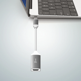 A white and silver USB-C to HDMI adapter cable connected to a silver laptop, shown against a light gray background.