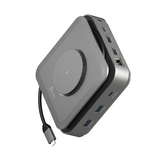 A compact 15-inch portable desktop computer in dark gray aluminum, shown at an angle to display its ports and attached power cable on a solid white background.