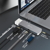 A silver jStorage USB-C to USB-A adapter kit shown on a dark textured desk next to a laptop, with labeled accessories including cables and a combo audio jack.