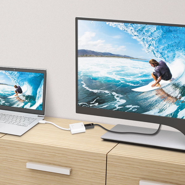 j5create JDA158 DisplayPort to 4K HDMI Active Adapter Two screens displaying a surfer on a wave, one larger and one smaller, on a wooden desk.
