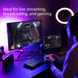 Person streaming or broadcasting on a computer setup with multiple monitors and gaming equipment.