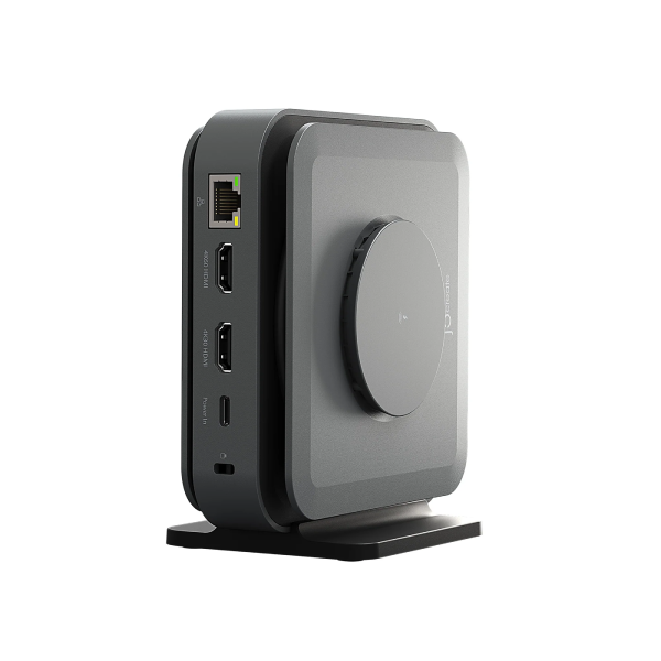 A compact square electronic device with rounded corners, shown in a three-quarter view on a white background. The device has a dark gray front face with a circular dial, a black side panel with ports, and a black stand.