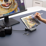 Person using a stylus to draw on a tablet with a dog illustration, connected to a monitor displaying the same image.