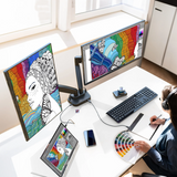 Person working at a desk with multiple monitors displaying colorful artwork.