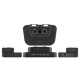 Black 3D virtual reality headset and base station kit on a white background, showing the front of the headset, the base unit, and two side modules.